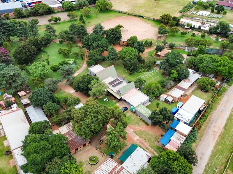 Aerial view of a small holding property featuring multiple outbuildings, extensive garden areas, and solar panel installations on the main roof structure.