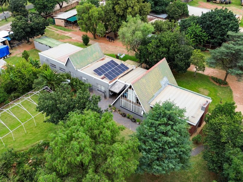 Aerial view of a small holding property featuring a main dwelling with solar panels, multiple outbuildings, and extensive garden grounds.