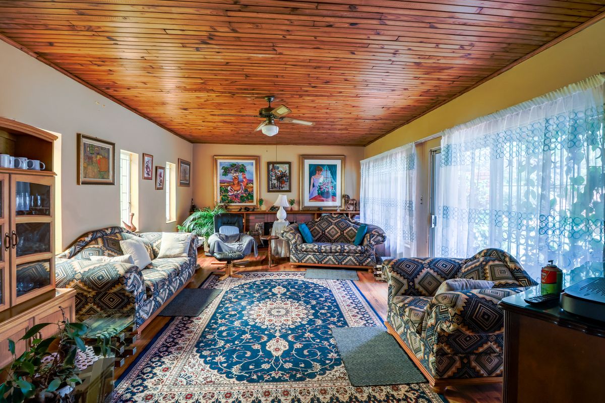 Spacious living room featuring a warm timber tongue and groove ceiling, hardwood flooring, and large sliding glass doors providing natural light.
