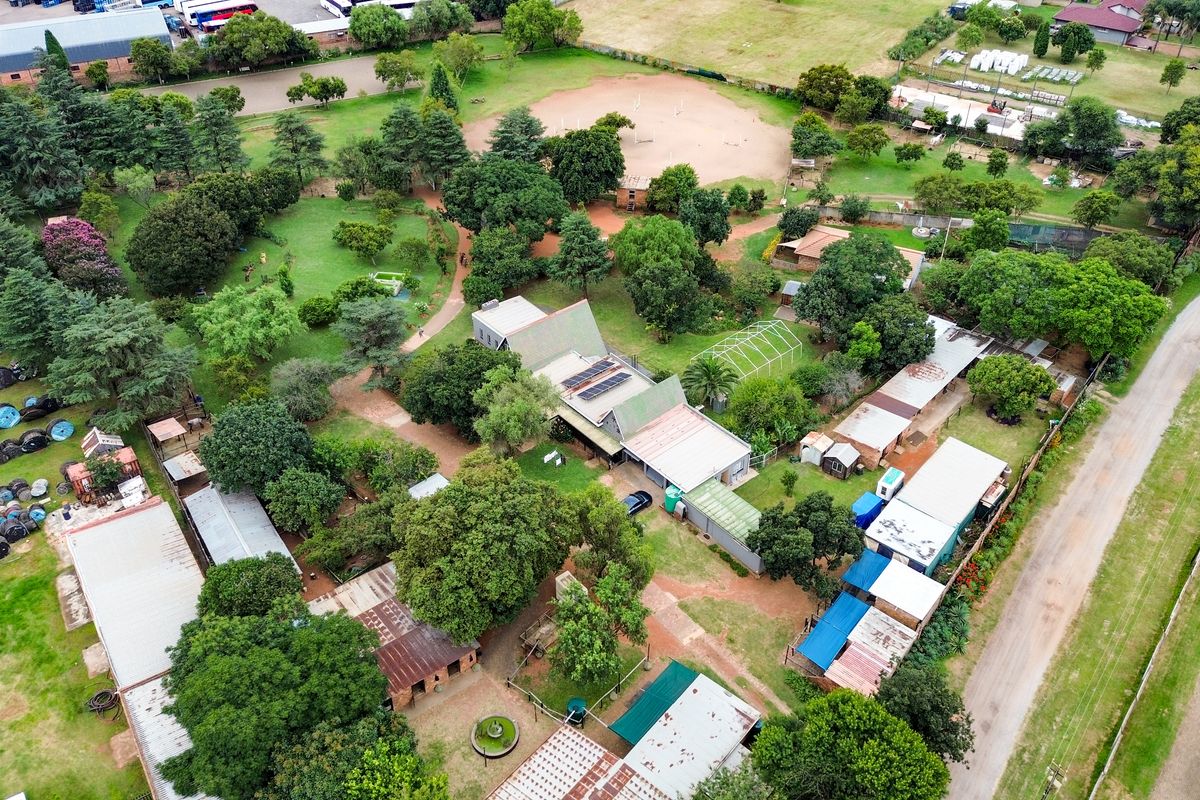 Aerial view of a small holding property featuring multiple outbuildings, extensive garden areas, and solar panel installations on the main roof structure.