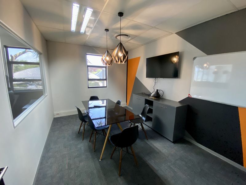 A modern, well-maintained office space featuring carpeted flooring, suspended ceiling with integrated lighting, and built-in storage cabinetry.