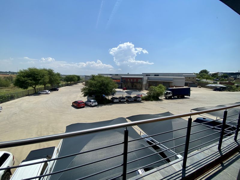 Elevated view overlooking a paved industrial parking lot with shade cloth structures and surrounding landscaping.