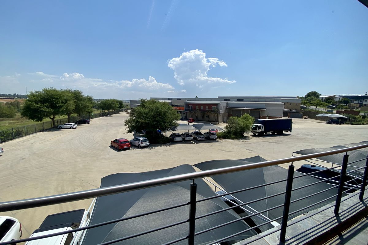Elevated view overlooking a paved industrial parking lot with shade cloth structures and surrounding landscaping.