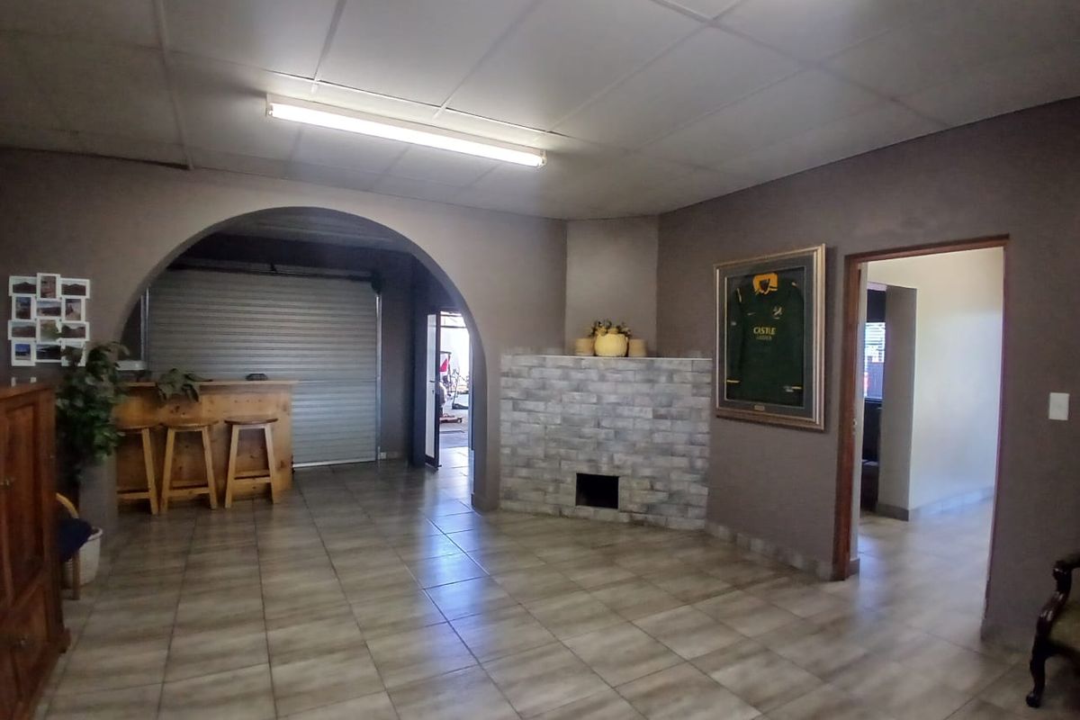 Spacious living area featuring tiled flooring, a central brick fireplace, and an arched entryway leading to an adjacent space.