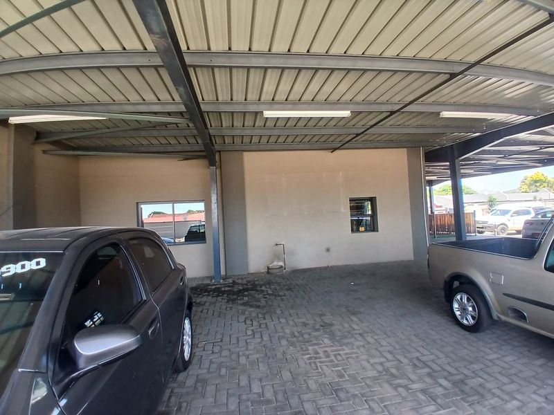 A covered parking area featuring a metal roof structure, paved flooring, and integrated lighting, suitable for commercial vehicle storage.