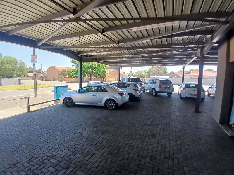 A covered parking area featuring a steel carport structure and paved flooring, providing sheltered vehicle storage for the commercial property.