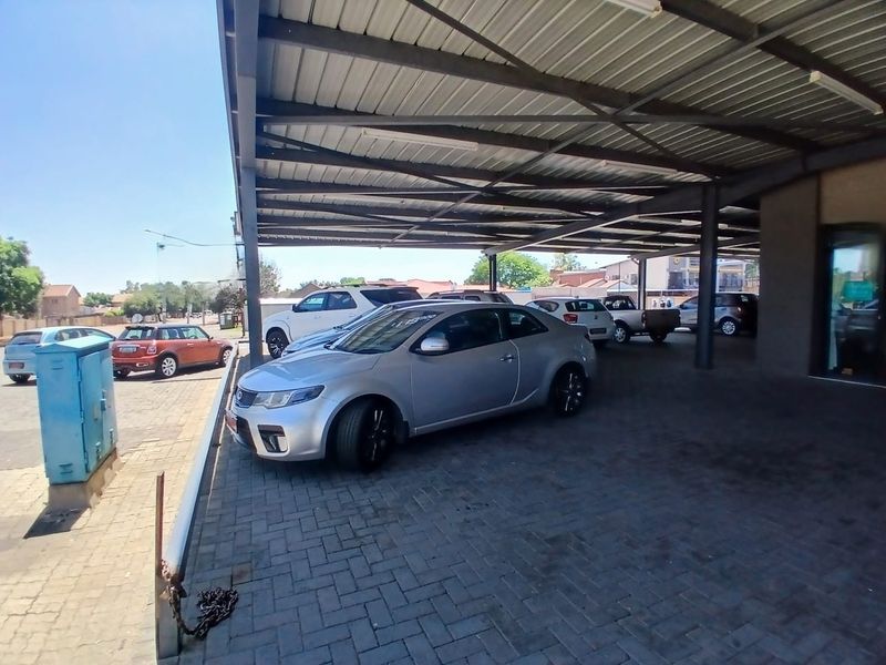 A commercial property featuring a large covered parking area with paved surfacing and steel structural supports.