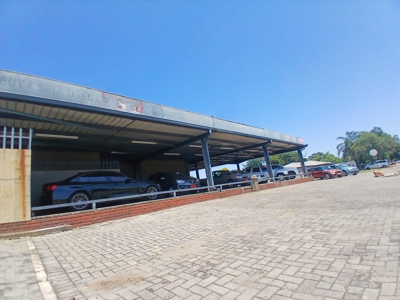 Commercial property featuring a large covered parking area with brick paving and a steel-framed structure, suitable for vehicle display or client parking.