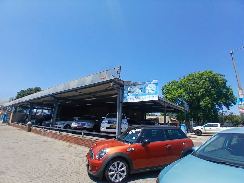 Commercial property featuring a large open-sided steel canopy structure with paved frontage, suitable for vehicle display or covered parking.