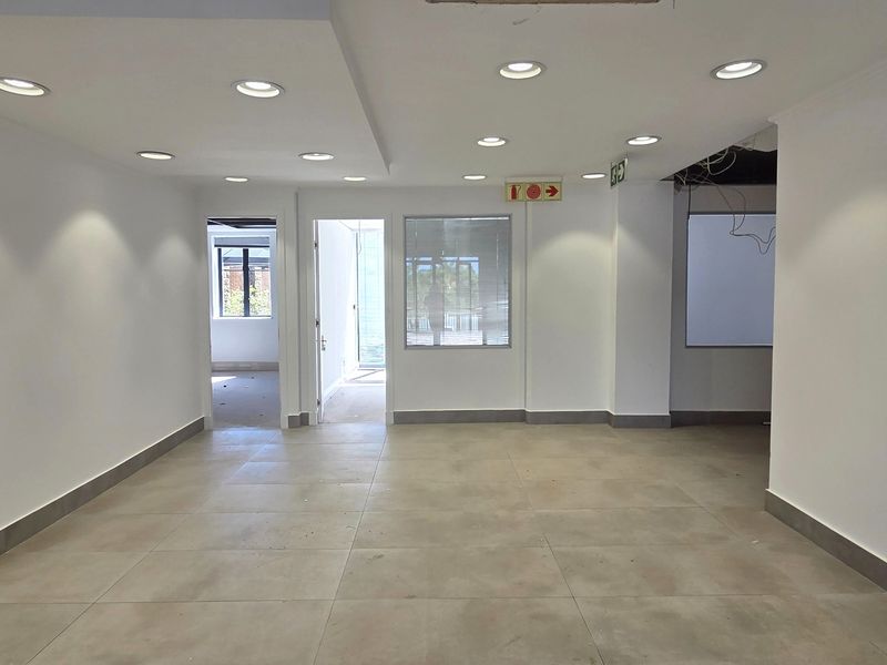 An open-plan office space featuring neutral tiled flooring, recessed downlighting, and clean white walls, currently vacant and ready for custom fit-out.