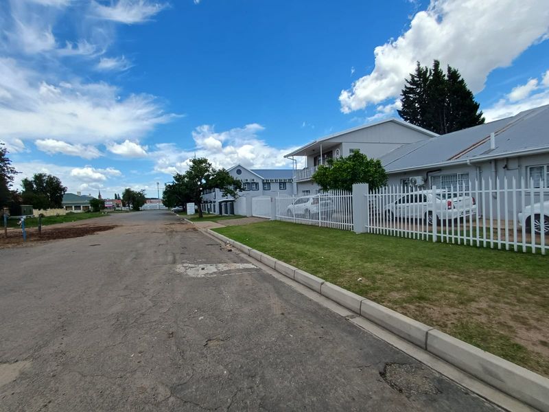 Street view of the property featuring a secure perimeter fence, paved driveway, and well-maintained exterior building facade.