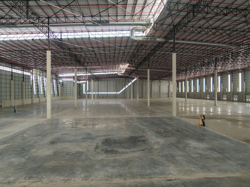 Expansive industrial warehouse space featuring high ceilings with exposed steel trusses, polished concrete flooring, and large-scale open floor plan suitable for logistics or manufacturing.