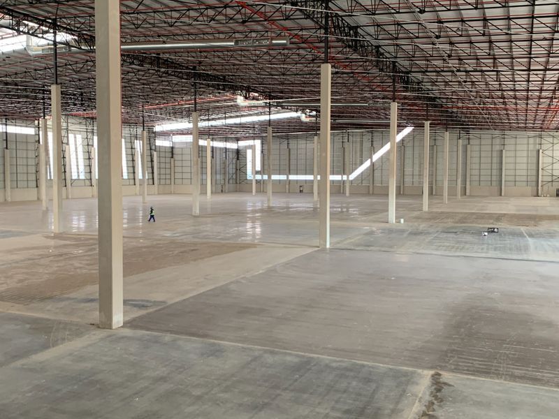 Expansive industrial warehouse space featuring high ceilings with exposed steel trusses, polished concrete flooring, and integrated fire sprinkler systems.