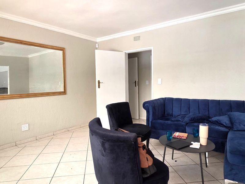 A living area featuring tiled flooring, crown molding, and neutral wall finishes, providing a functional space for commercial or office use.
