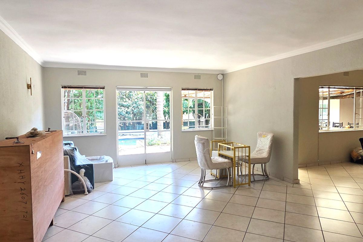 Spacious open-plan living area featuring neutral tiled flooring, large windows, and sliding glass doors providing direct access to the outdoor pool area.