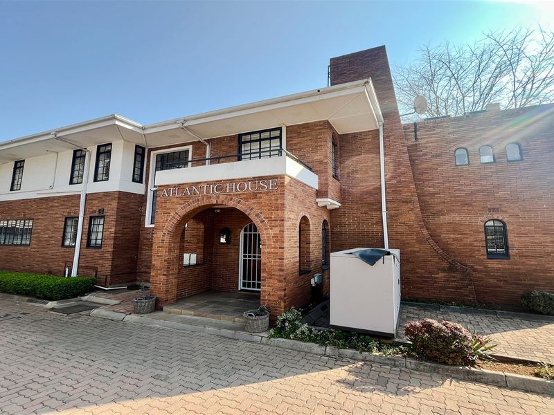 Front exterior view of Atlantic House, featuring a classic brick facade, arched entrance, and paved driveway access.