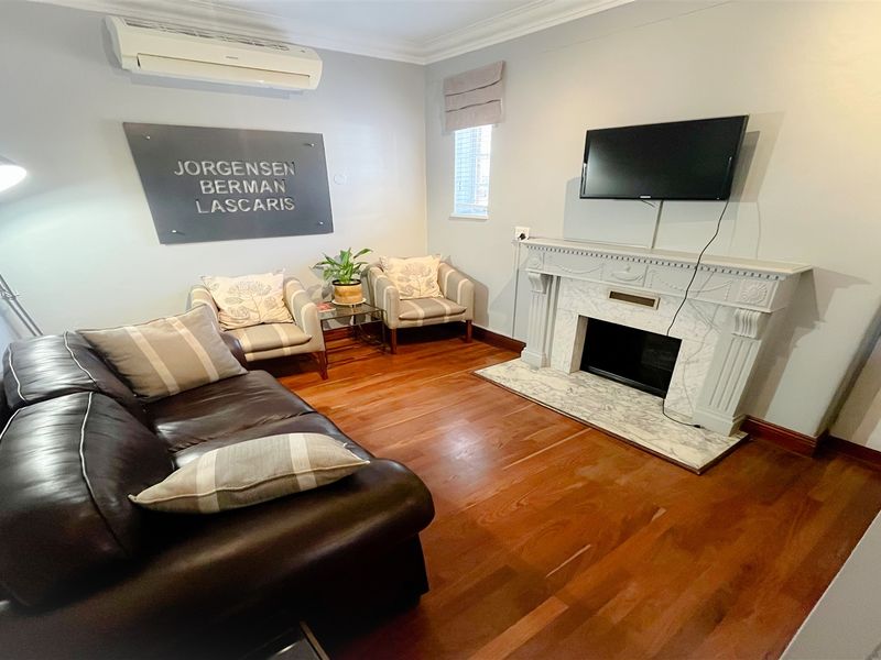 A professional office space featuring polished hardwood flooring, a decorative fireplace mantel, and a wall-mounted air conditioning unit.