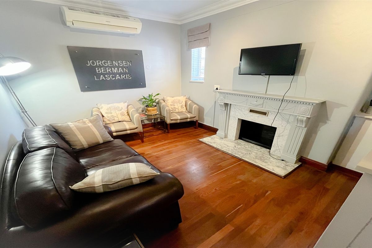 A professional office space featuring polished hardwood flooring, a decorative fireplace mantel, and a wall-mounted air conditioning unit.