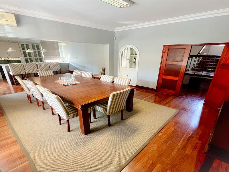 Spacious open-plan dining and kitchen area featuring polished hardwood flooring, crown molding, and elegant built-in cabinetry with a dedicated display niche.
