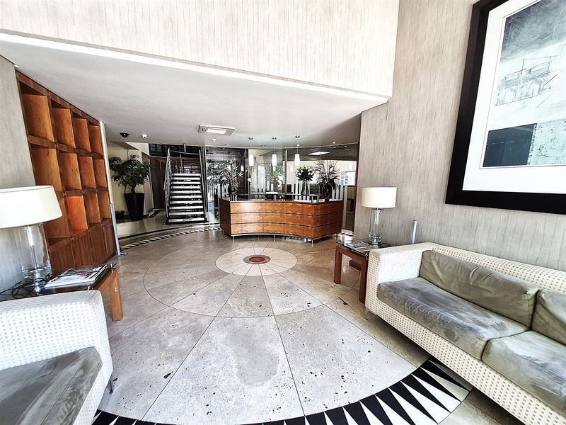 Professional office reception area featuring a curved built-in desk, stone flooring, and a feature staircase leading to upper levels.