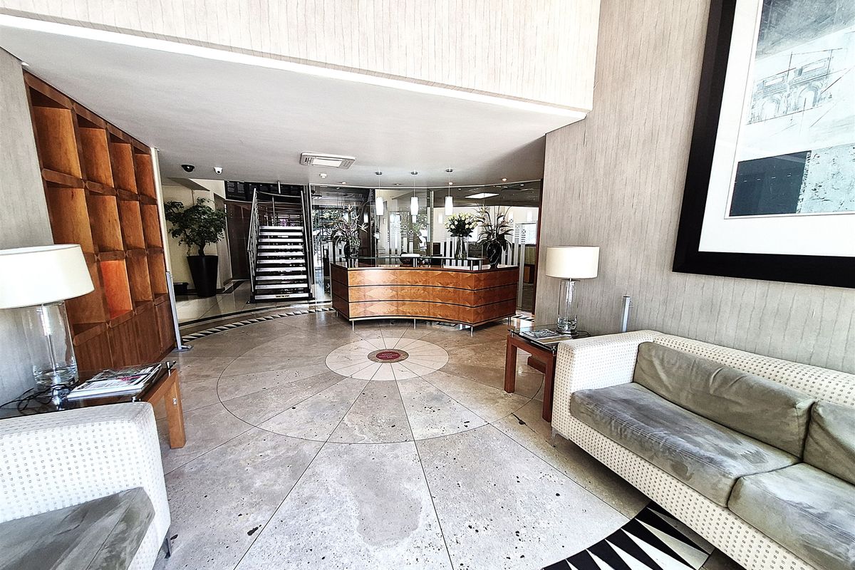 Professional office reception area featuring a curved built-in desk, stone flooring, and a feature staircase leading to upper levels.