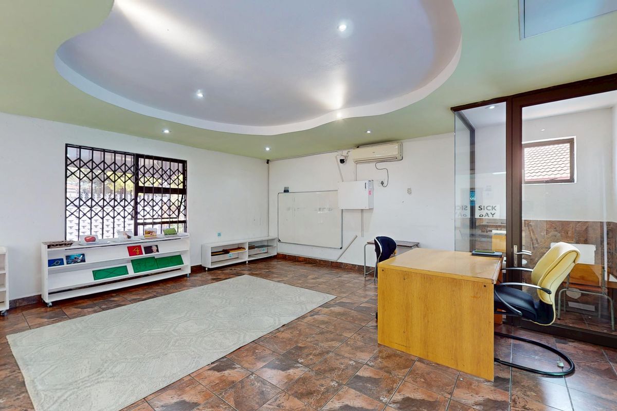 A functional commercial office space featuring tiled flooring, a coved ceiling with recessed lighting, a glass partition, and integrated air conditioning.