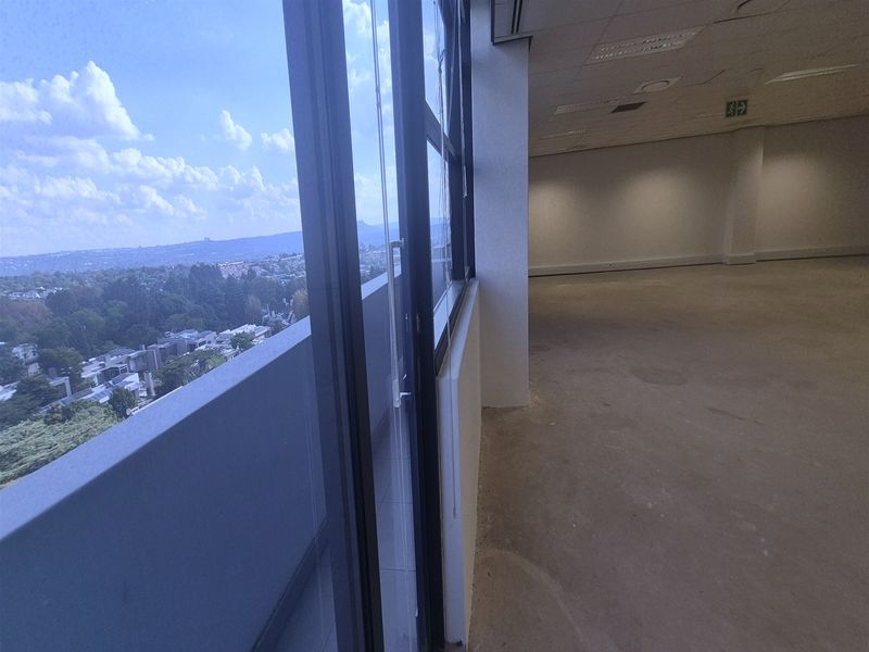 An expansive, empty office space featuring large windows with panoramic views, recessed ceiling lighting, and neutral finishes, ready for custom fit-out.