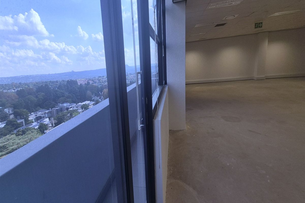 An expansive, empty office space featuring large windows with panoramic views, recessed ceiling lighting, and neutral finishes, ready for custom fit-out.