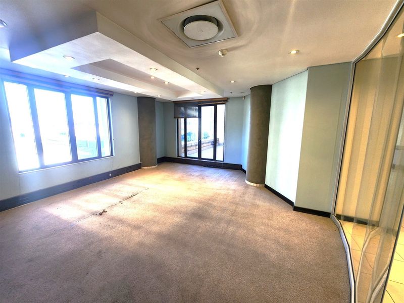 Spacious empty office area featuring large windows, recessed ceiling lighting, central air conditioning, and a glass partition wall.