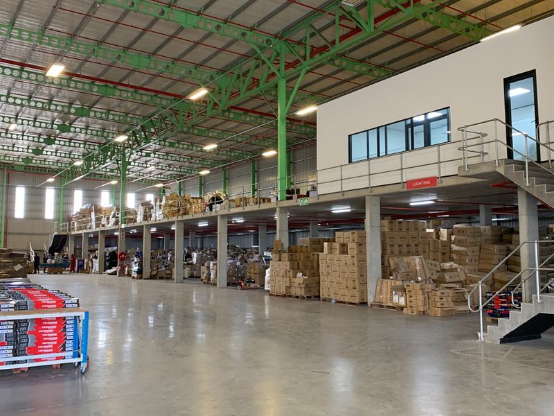 Spacious industrial warehouse featuring a mezzanine level, concrete flooring, steel support columns, and an integrated staircase for efficient storage and operational access.