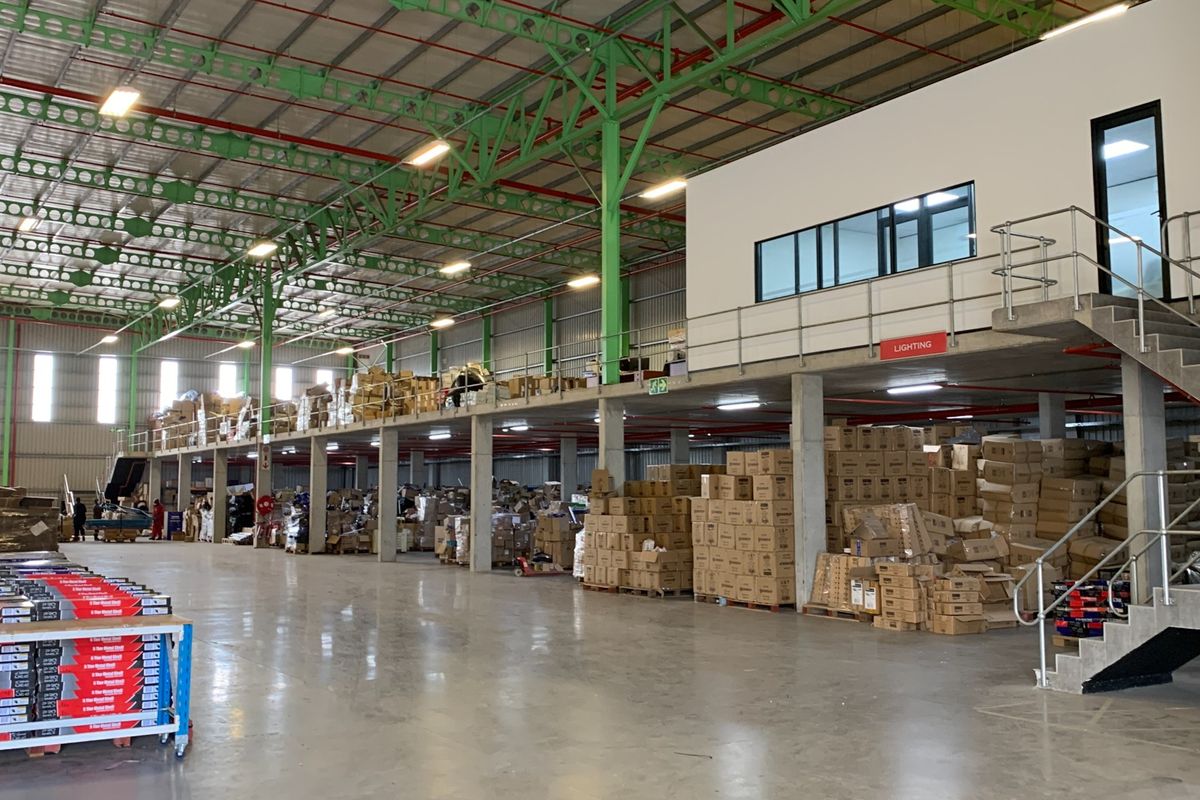 Spacious industrial warehouse featuring a mezzanine level, concrete flooring, steel support columns, and an integrated staircase for efficient storage and operational access.