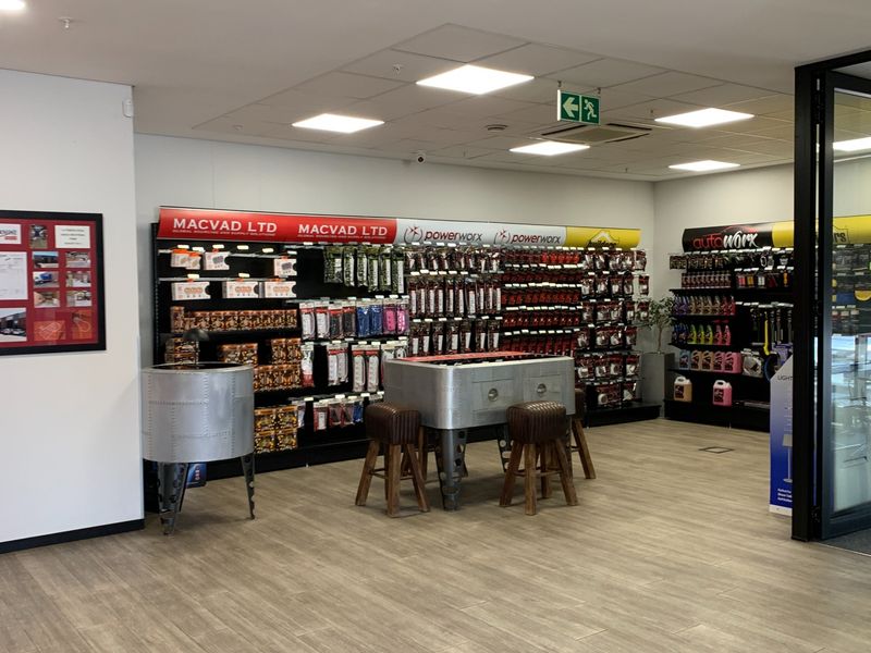 A well-maintained industrial retail showroom space featuring modern recessed lighting, suspended ceiling tiles, and durable laminate flooring with organized product display shelving.