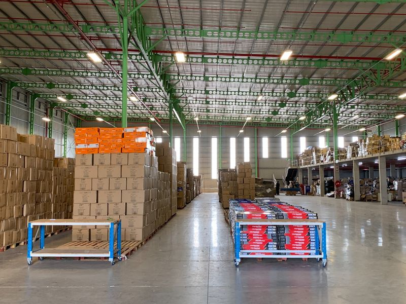 Spacious industrial warehouse featuring high ceilings with exposed steel trusses, polished concrete flooring, integrated mezzanine level, and functional overhead lighting.