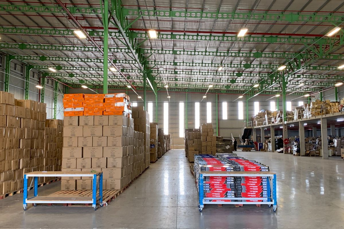 Spacious industrial warehouse featuring high ceilings with exposed steel trusses, polished concrete flooring, integrated mezzanine level, and functional overhead lighting.