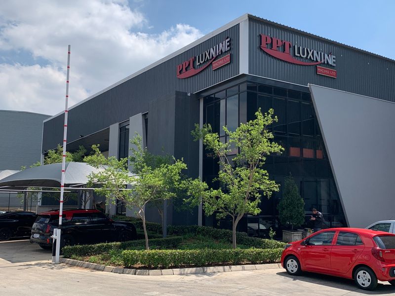 Modern industrial commercial building featuring contemporary metal cladding, extensive glass facade, and dedicated shade-covered parking area.