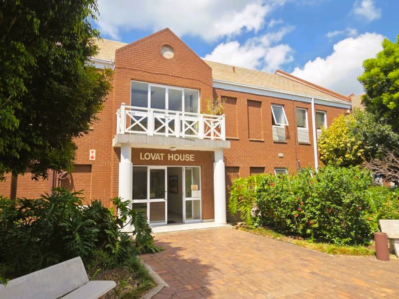 Front exterior view of Lovat House, featuring a classic brick facade, a small balcony, and a paved entrance area.