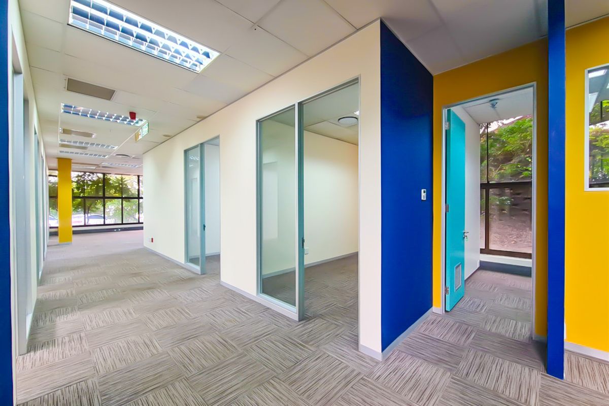Modern office space featuring glass partitions, carpet tiles, and bright accent walls, offering a clean and professional environment for business operations.
