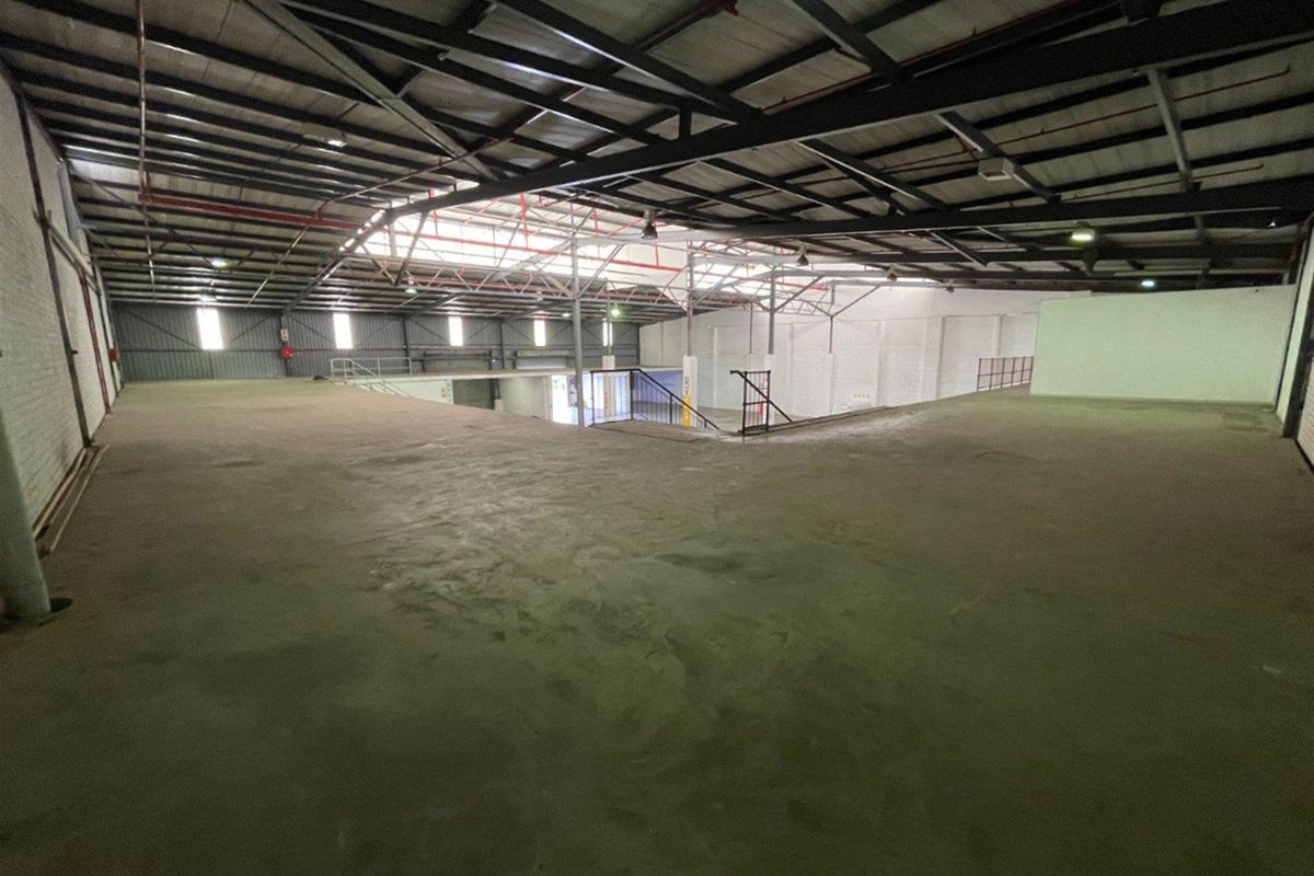 Spacious industrial mezzanine level featuring exposed steel roof trusses, concrete flooring, and metal wall cladding, suitable for storage or light industrial operations.