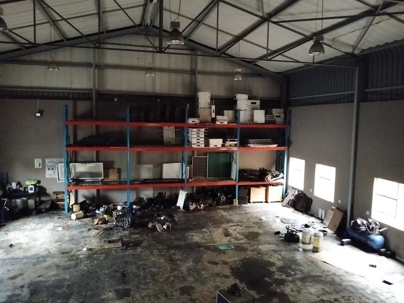 Spacious industrial warehouse unit featuring high ceilings with exposed steel trusses, concrete flooring, and integrated heavy-duty steel racking systems.