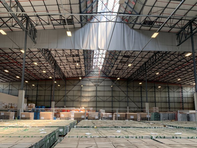 Spacious industrial warehouse featuring a high-clearance steel truss roof, integrated skylights, fire sprinkler system, and expansive metal-clad walls suitable for storage or manufacturing operations.
