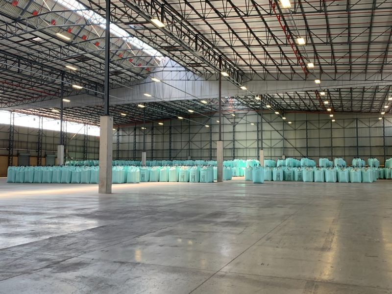Spacious industrial warehouse featuring high-clearance exposed steel truss roofing, polished concrete flooring, and extensive overhead lighting, currently utilized for bulk storage.