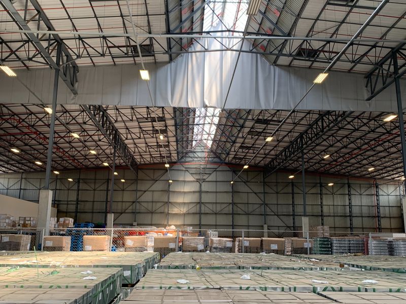 Large industrial warehouse space featuring high steel truss ceilings, integrated skylights, and durable concrete flooring, suitable for storage or manufacturing operations.