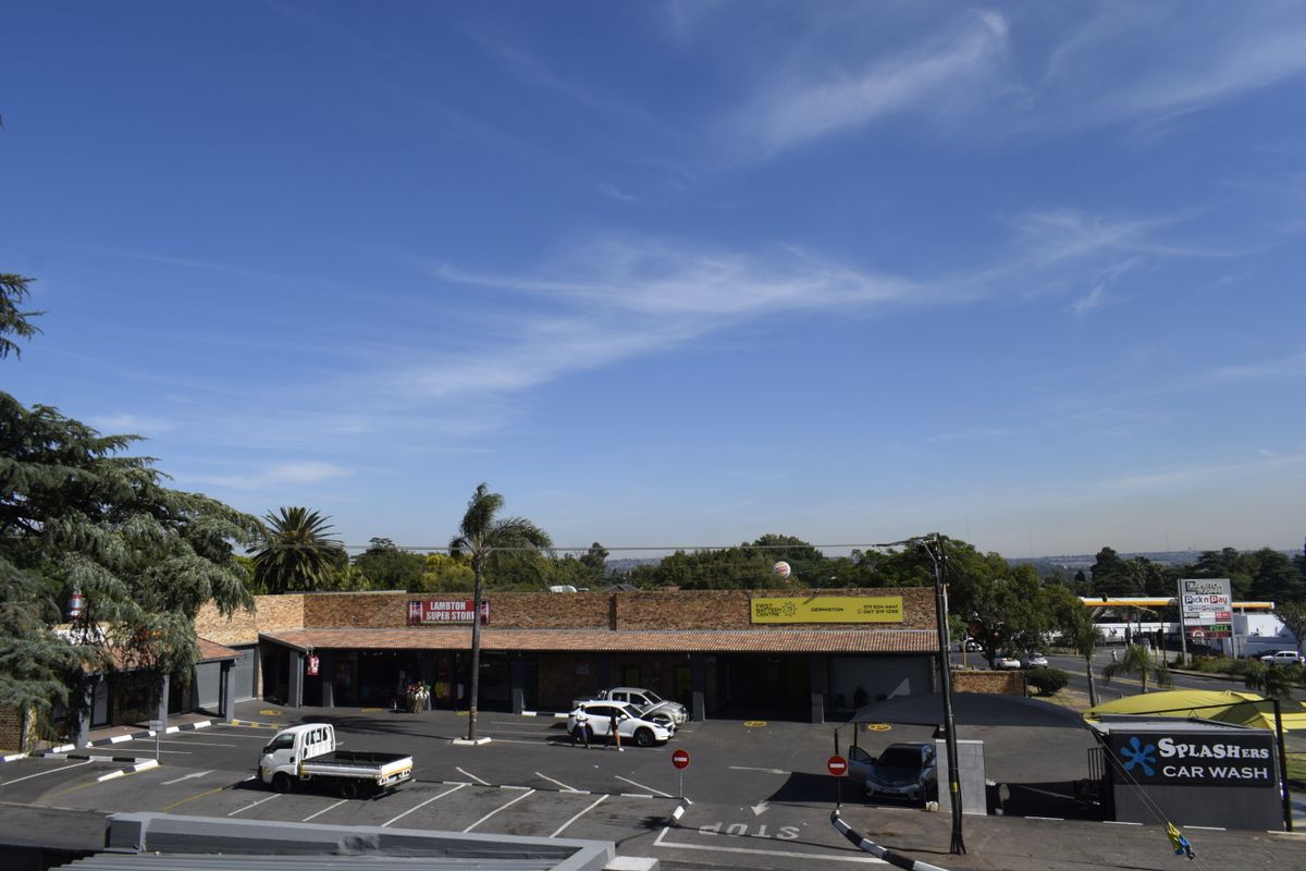 Aerial view of a commercial retail center featuring a brick facade, paved parking area, and an integrated car wash facility.