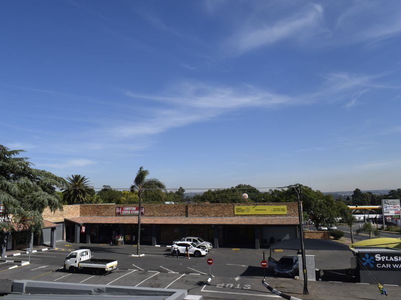 Aerial view of a commercial retail center featuring a brick facade, paved parking area, and an integrated car wash facility.
