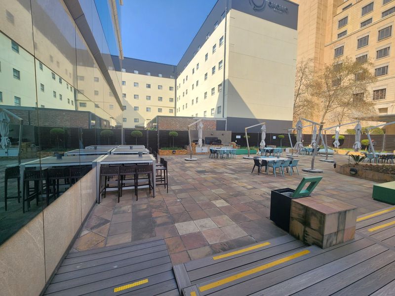 Spacious outdoor terrace featuring paved flooring, timber decking, and a built-in counter area, suitable for corporate events or office break-out space.