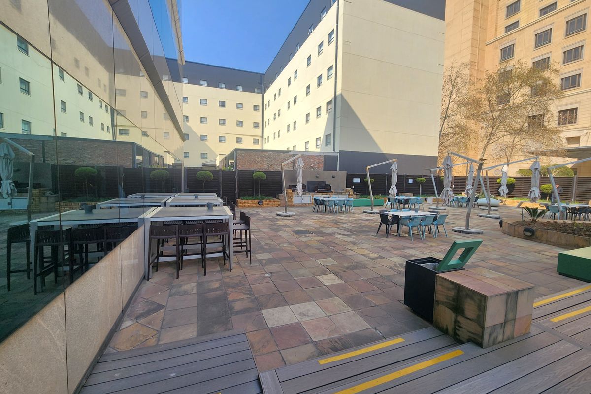 Spacious outdoor terrace featuring paved flooring, timber decking, and a built-in counter area, suitable for corporate events or office break-out space.