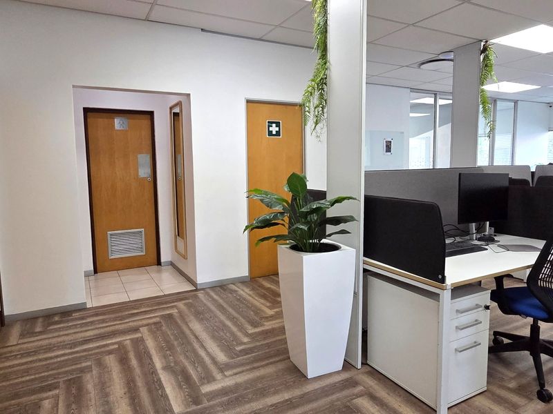 A professional office space featuring herringbone vinyl flooring, suspended ceilings, and access to internal facilities through flush panel doors.
