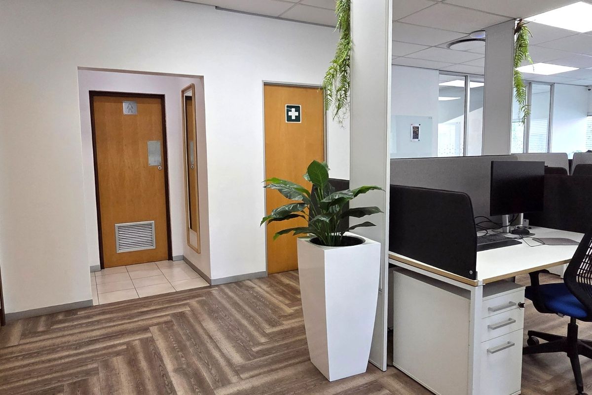 A professional office space featuring herringbone vinyl flooring, suspended ceilings, and access to internal facilities through flush panel doors.