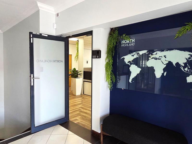 Professional office entrance featuring a frosted glass door, biometric security system, and a modern navy accent wall with branded signage.