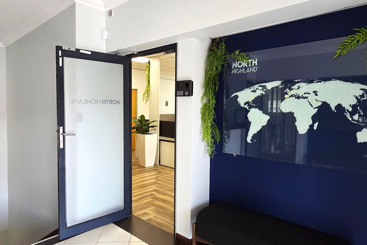 Professional office entrance featuring a frosted glass door, biometric security system, and a modern navy accent wall with branded signage.